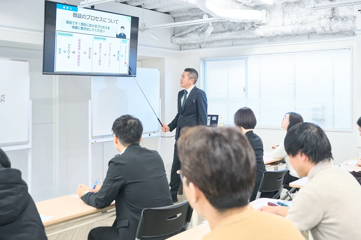 青型モニターに映ったスライドを指しながら説明をしている研修の様子