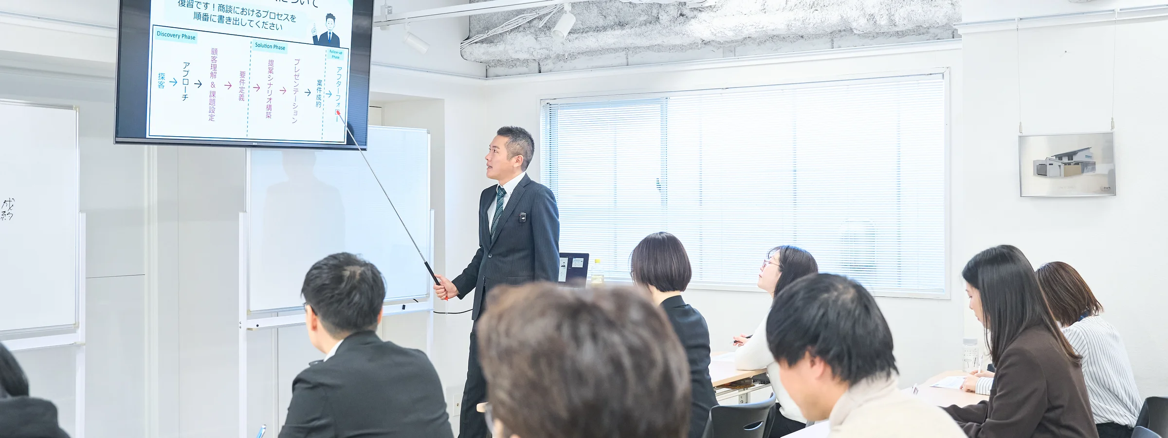 青型モニターに映ったスライドを指しながら説明をしている研修の様子