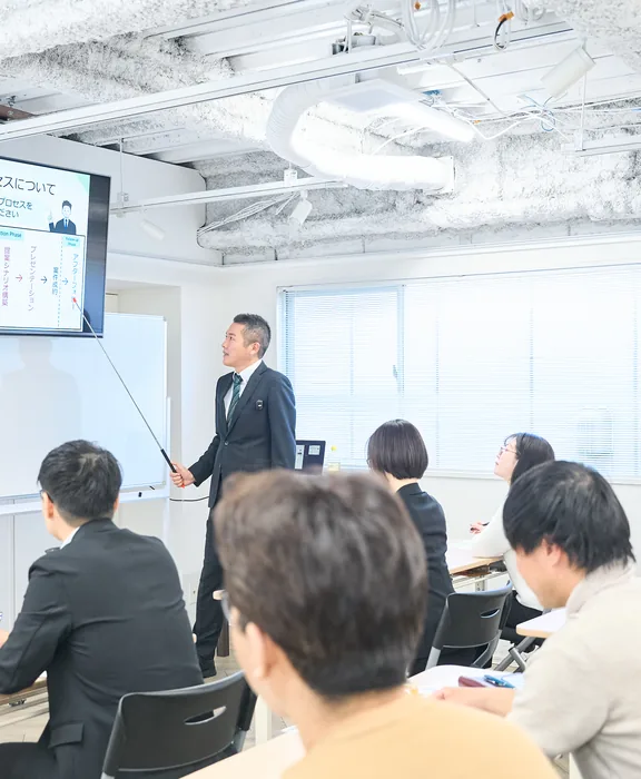 大型モニターに映し出されたスライドを指しながら説明をしている。