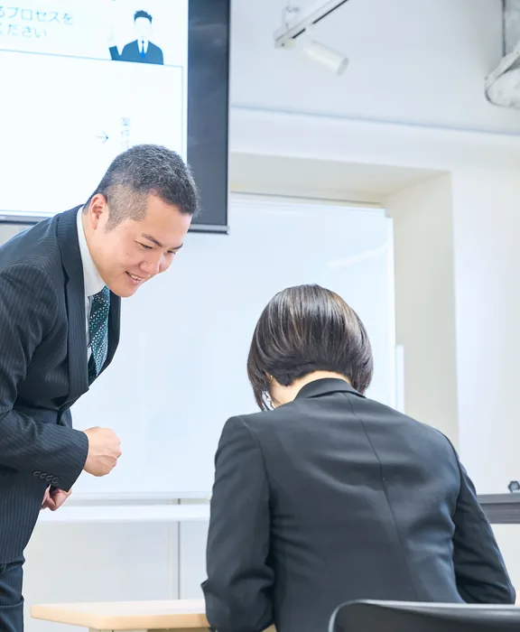 受講生に対して講師が笑顔で話しかけている。